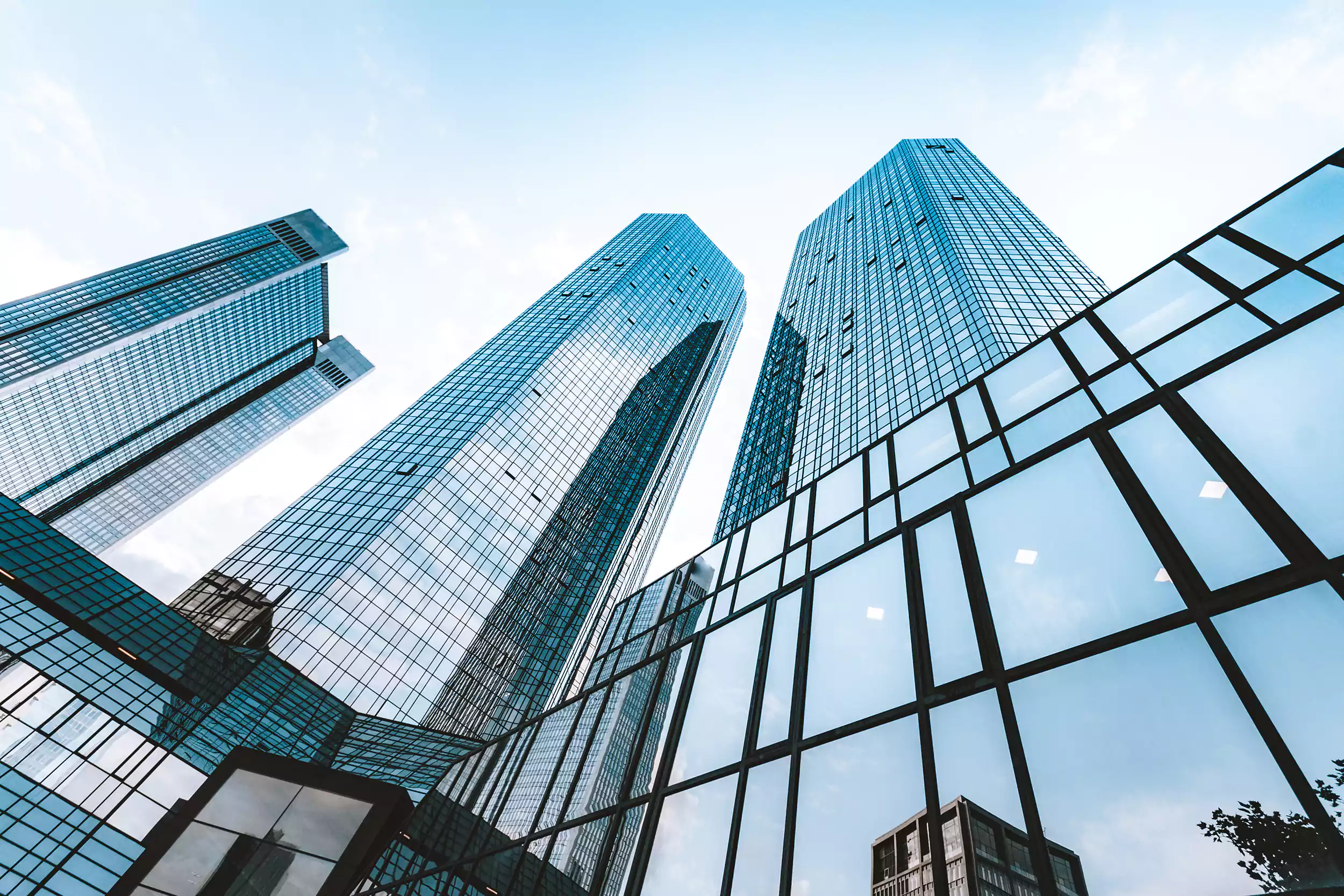 Modern glass commercial towers viewed from below against a blue sky