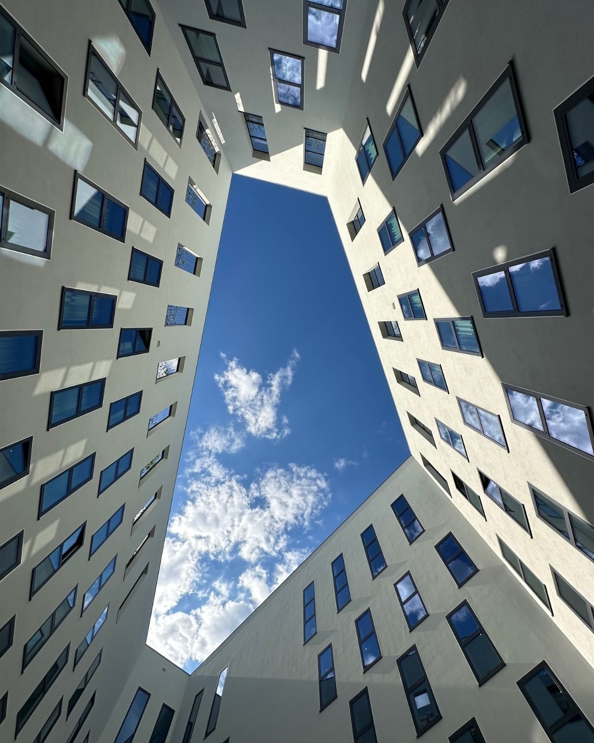 Looking up through the courtyard of a multi-storey commercial building towards open sky